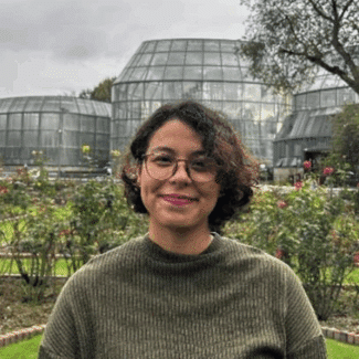 Amanda López Amorim smiling at the camera in front of a park.